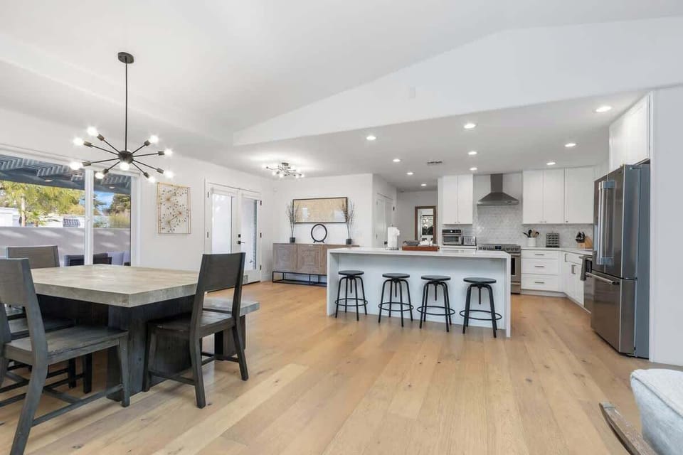 Your open-concept kitchen flows seamlessly into the dining area, featuring sleek white cabinetry, modern appliances, and a spacious island perfect for meals.
