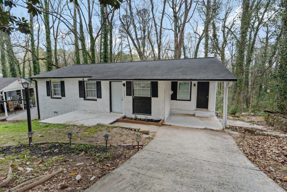 Charming exterior with a private driveway and peaceful, wooded surroundings for 