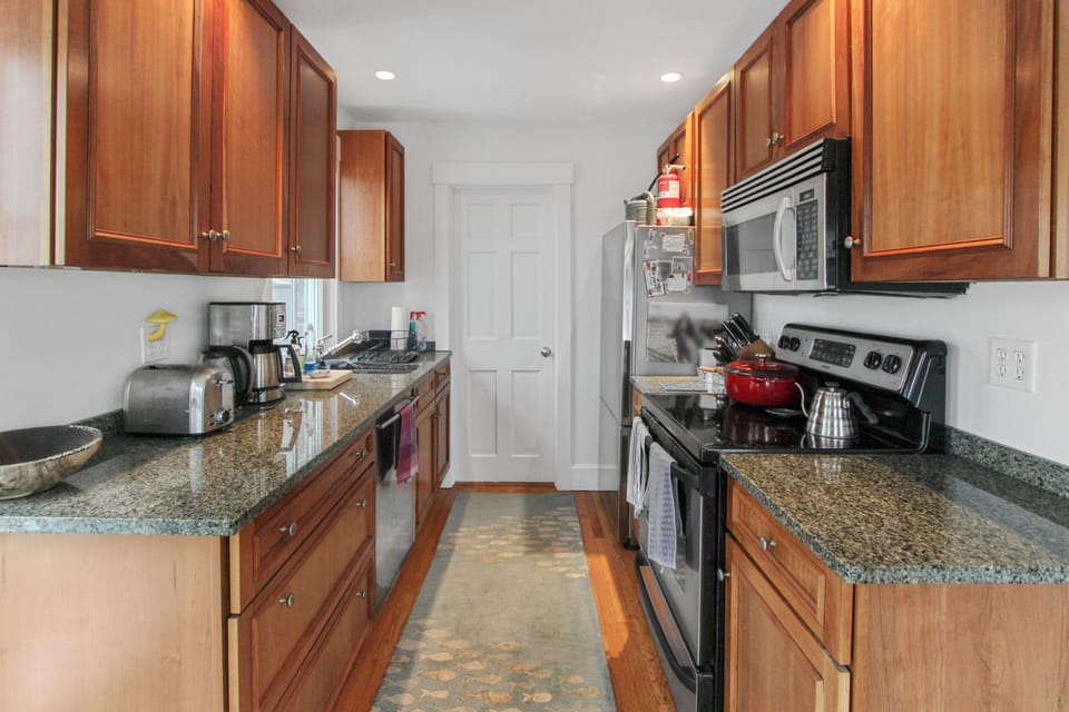 Your fully equipped galley kitchen features granite countertops, rich wood cabinets, and stainless steel appliances for creating memorable meals.