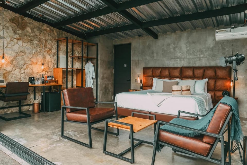 Sink into crisp linens beneath bold leather headboard and concrete walls.