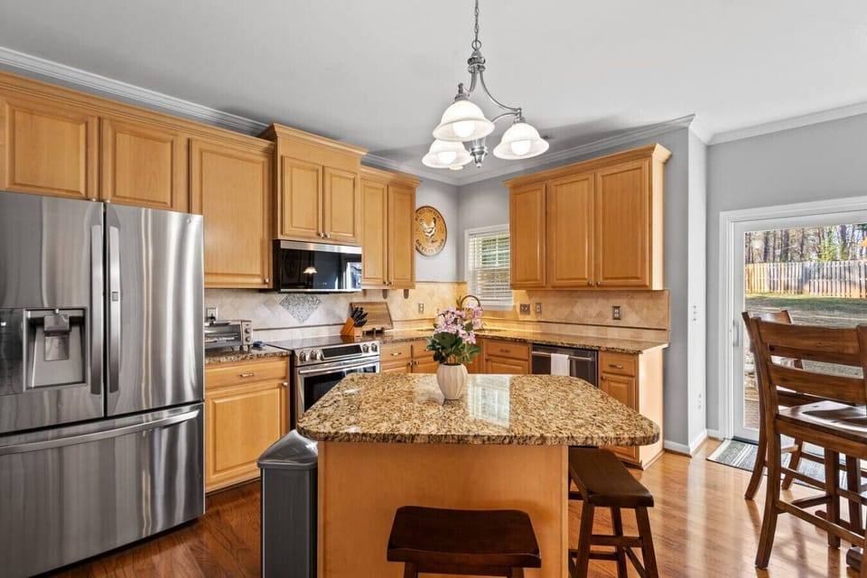 Spacious kitchen featuring granite countertops, island seating, and modern stainless steel appliances.