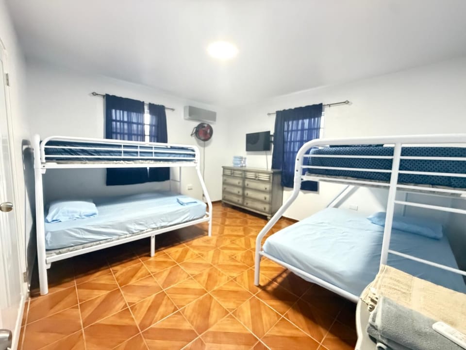Guest bedroom with two cozy twin/full bunk beds, a dresser, and TV.