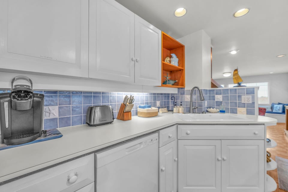 Your fully equipped kitchen features crisp white cabinets, charming blue tile backsplash, and modern appliances for preparing delicious home-cooked meals.