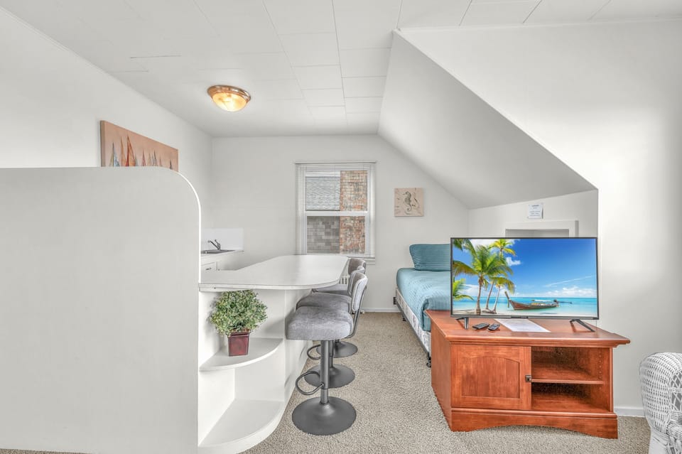 Relax in your bright attic retreat with cozy seating, modern kitchenette, and entertainment center—perfect for unwinding after exploring.