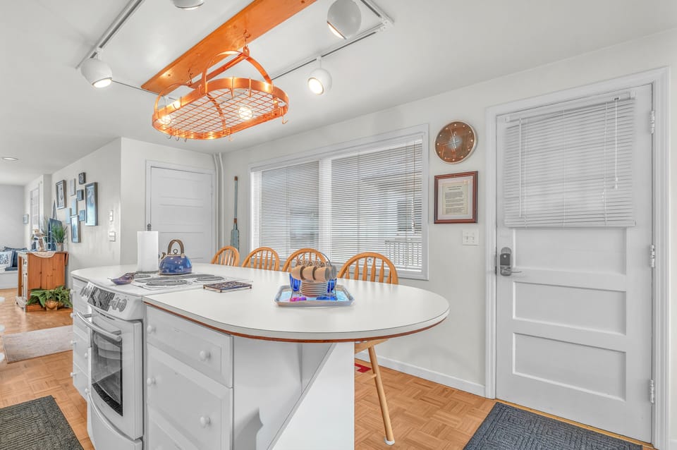 You'll love gathering around this bright kitchen island for meals and conversation, with its cheerful orange pendant light creating warmth overhead.