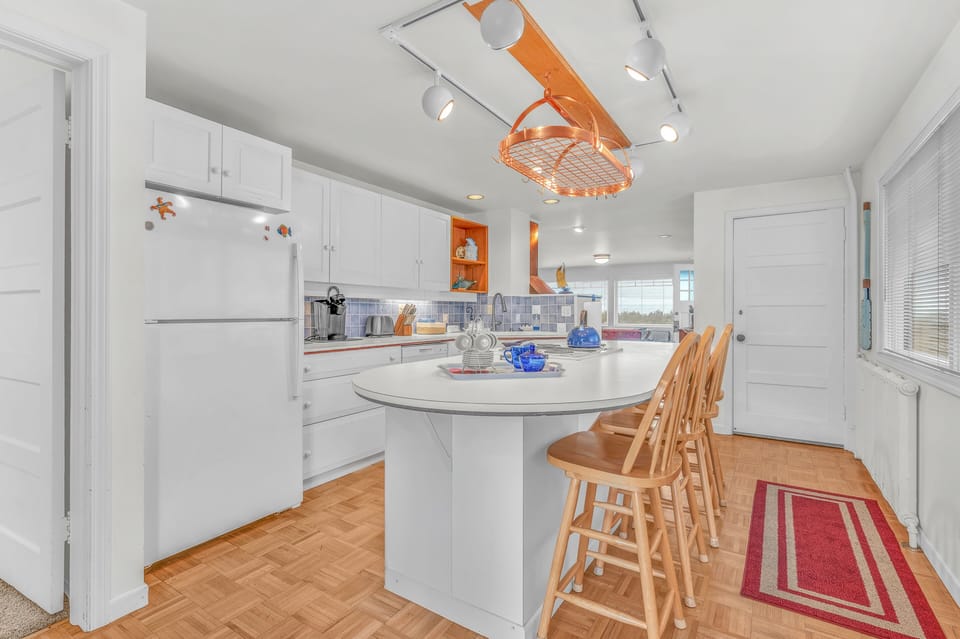 Your bright kitchen features a spacious island perfect for morning coffee and meal prep, with cheerful orange accents creating warmth.