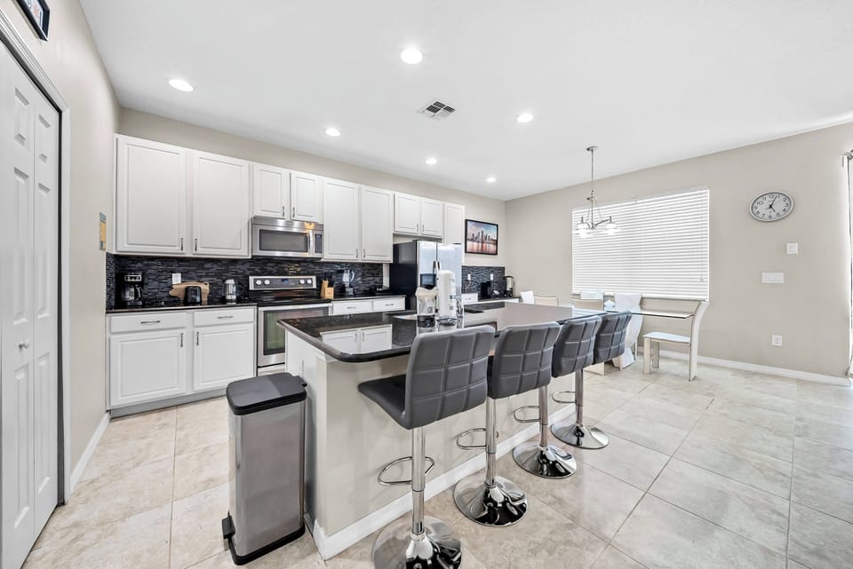 Enjoy a bright, spacious kitchen with sleek stainless steel appliances and white cabinetry. The large island with stylish bar stools is perfect for casual dining and lively conversations, making it the heart of your vacation.