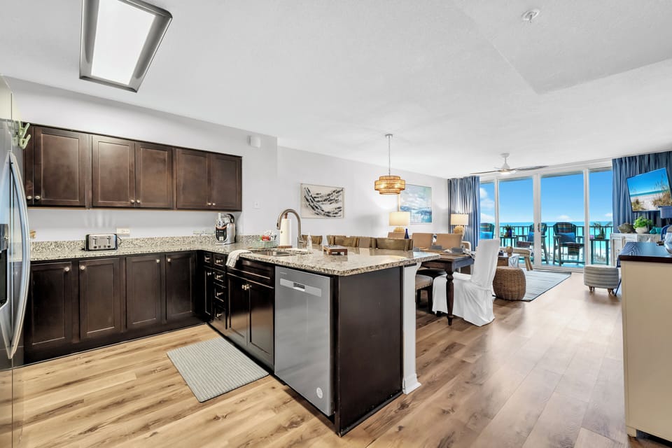 Picture yourself preparing meals in this bright, open kitchen while soaking in stunning ocean views. Sunlight streams through expansive windows, illuminating the granite counters and custom cabinetry—your perfect beach escape awaits.