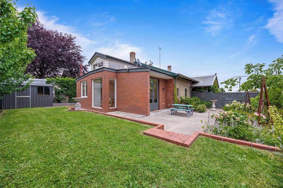 Expansive, fully fenced backyard with outdoor furniture. 