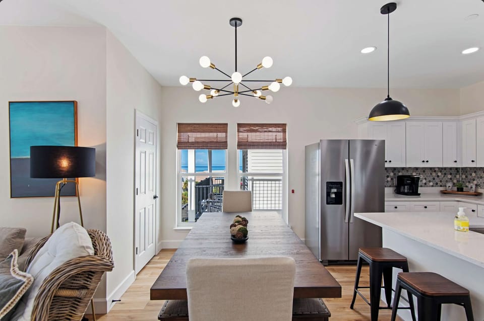 You'll love cooking and entertaining in this bright, modern kitchen featuring sleek white cabinets, a spacious island, and stylish statement lighting.