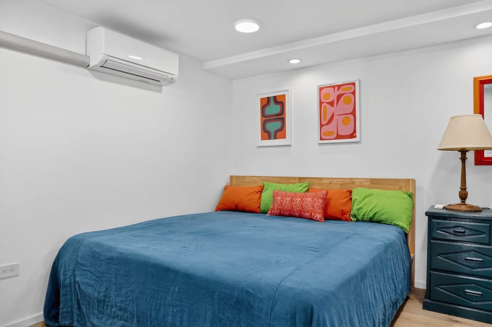 Cozy bedroom 4 with a blue bedspread, colorful pillows, and modern wall art accents.