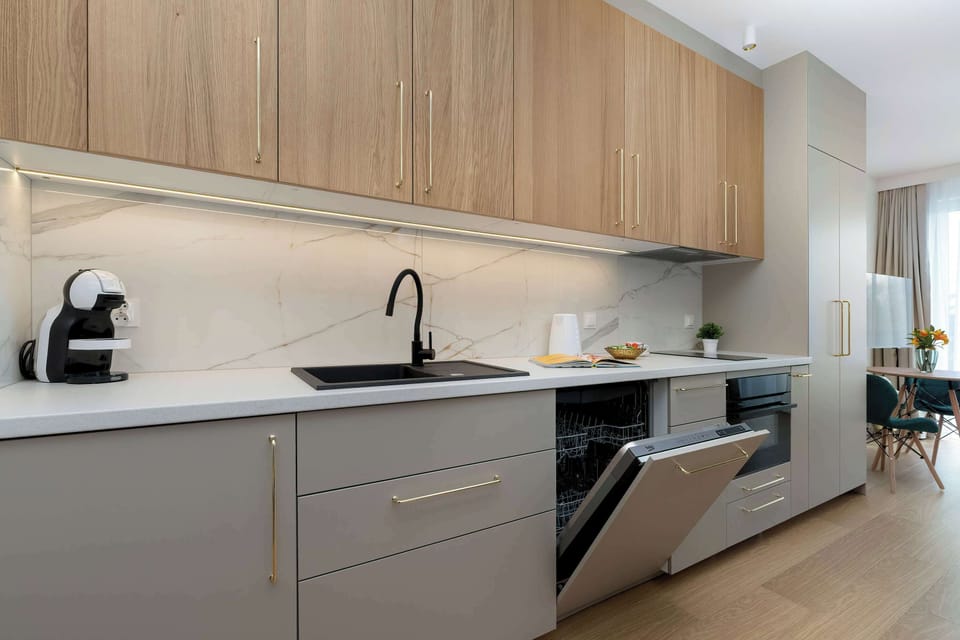 The kitchen layout is shown from an alternative angle, revealing a built-in dishwasher and a convenient coffee station. The continuity of the wooden cabinetry adds warmth to the functional space.