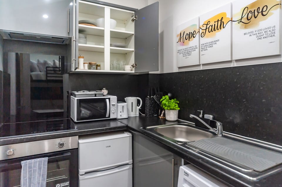 The kitchen is fully equipped with all utensils and appliances, including a mini oven, fridge, and washing machine with complimentary laundry detergent. Everything you need for a comfortable stay.