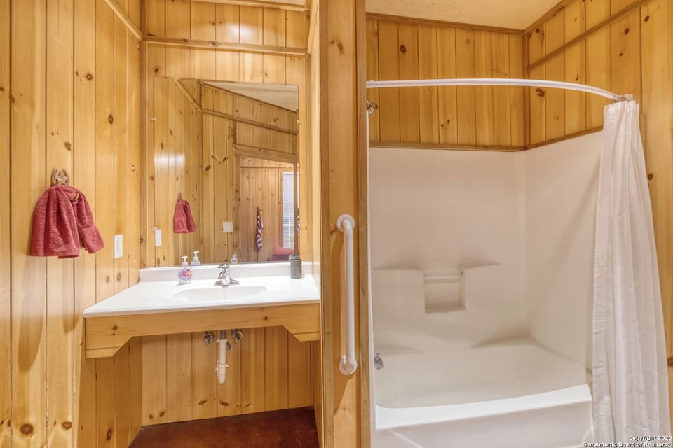 Tub/shower combo with grab bar, plus a spacious vanity and large mirror.