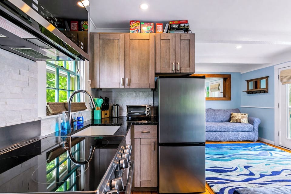 Bright kitchen-living area with stainless appliances, games, and cozy sofa