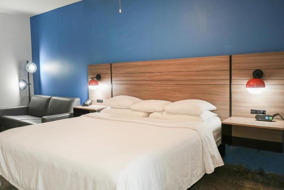 Sink into cloud-soft pillows beneath stylish bedside lighting.