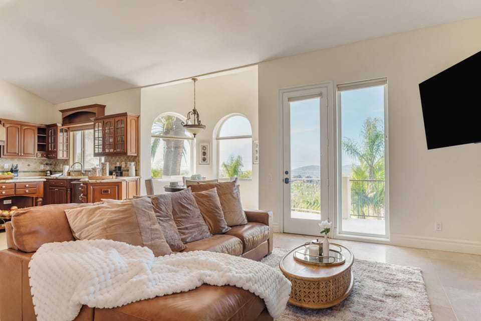 Third living room with a leather couch, TV and outdoor views.
