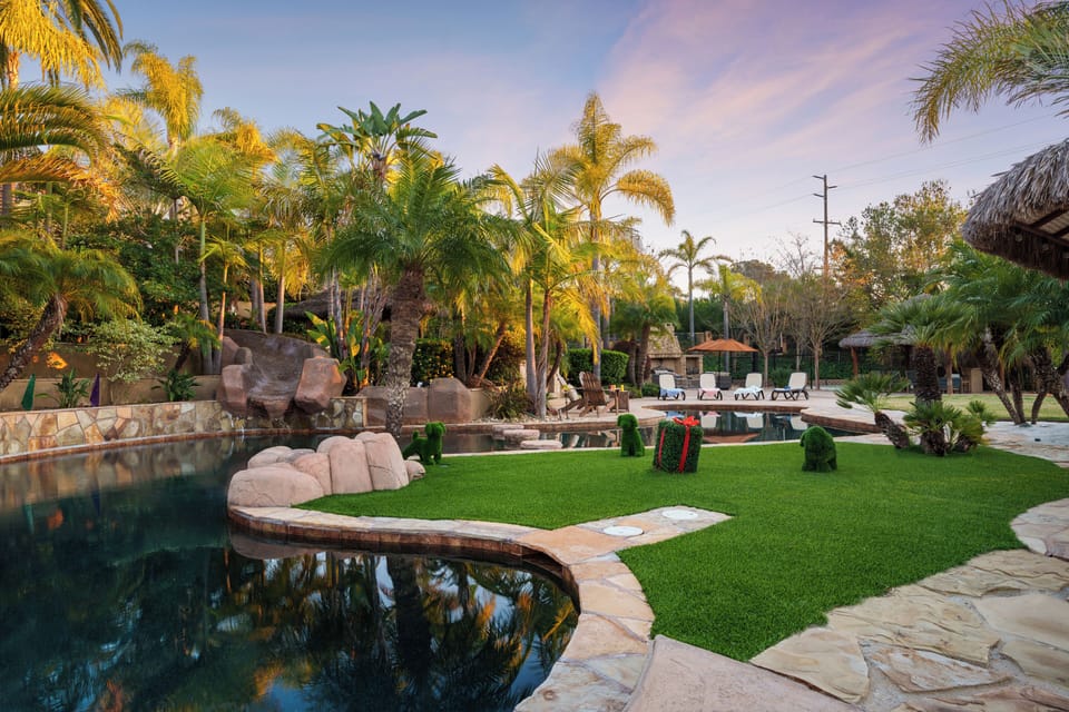 Resort‑style pool surrounded by lush palms, stone pathways, and inviting lounge seating.