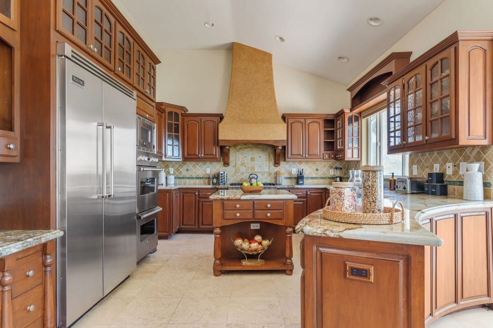 Warm, traditional kitchen with rich wood cabinetry, granite counters, and a spacious central island.
