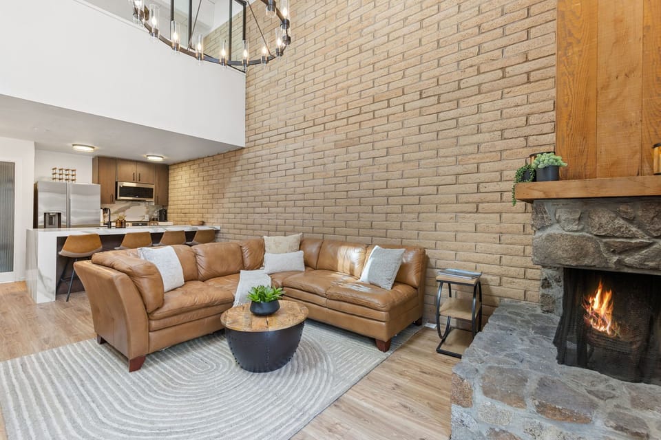Spacious living room with brick wall, fireplace, and loft overlook above