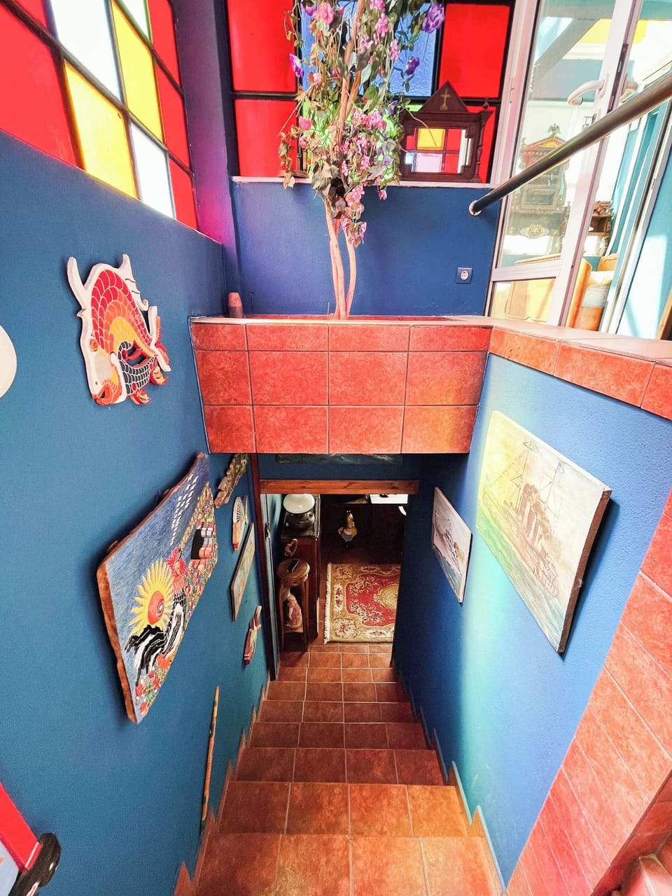 Colorful staircase connecting the two floors of the maisonette, featuring artistic stained-glass panels that fill the space with natural light