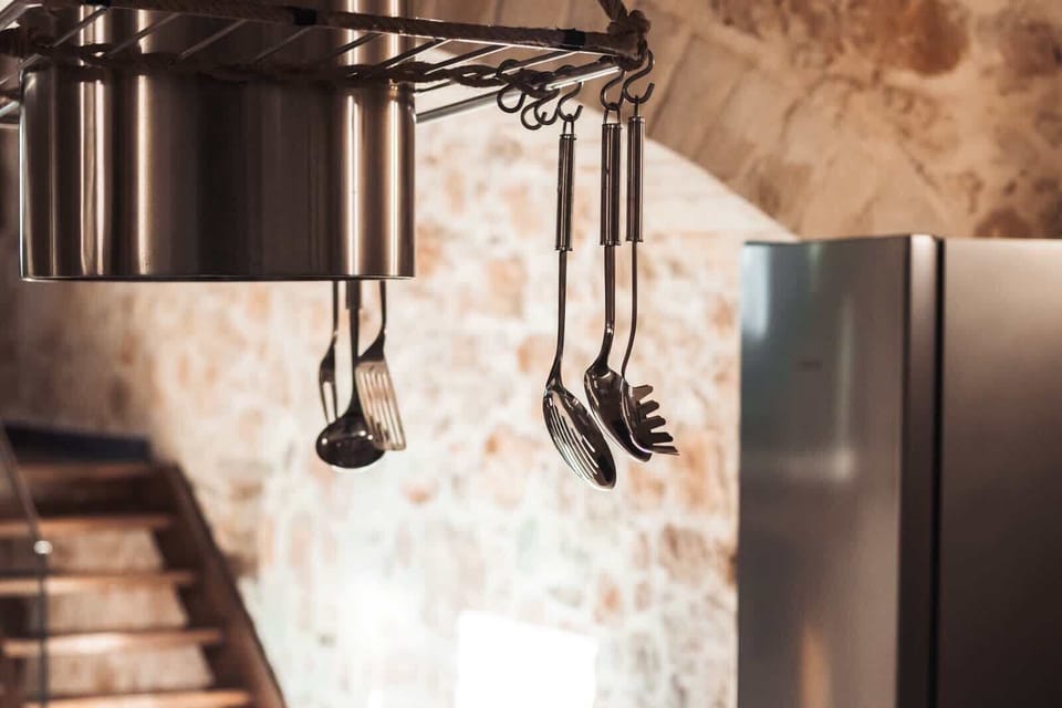 Kitchen details with hanging cookware and natural textures, reinforcing the traditional character of the space.