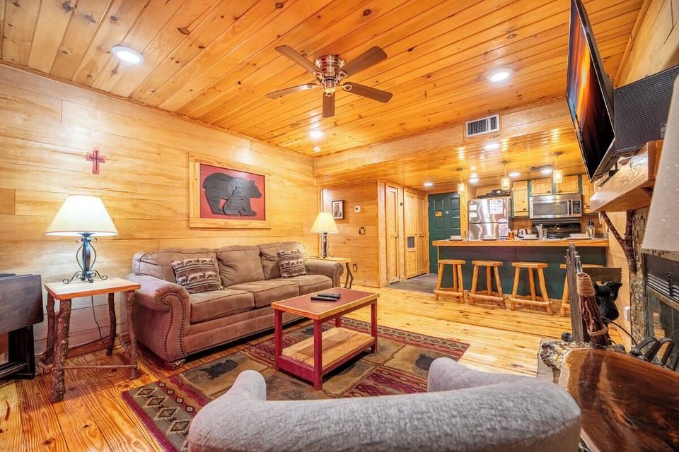 Cozy up in your rustic cabin retreat with warm wood paneling, comfortable seating, and a crackling fireplace for perfect mountain evenings.