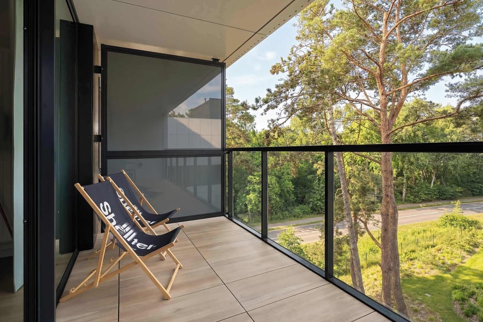 A balcony setup with chairs and a table, perfect for relaxing outdoors. Sunlight brightens the space.