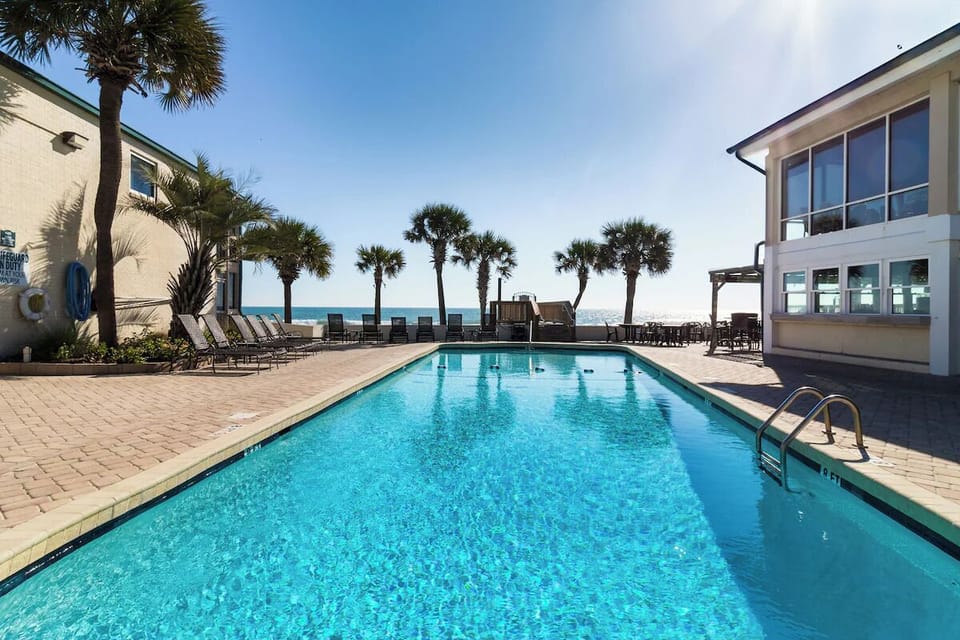 Dive into sunlit oceanfront pool bliss with swaying palms.