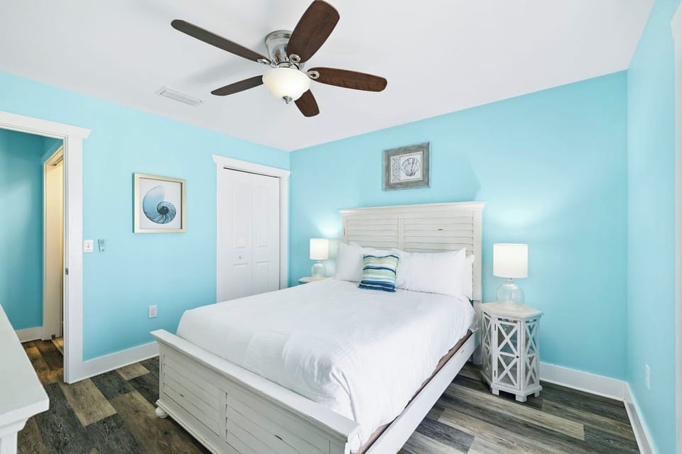 Drift off to sleep in this serene coastal bedroom, where calming turquoise walls and crisp white linens create your perfect seaside retreat.