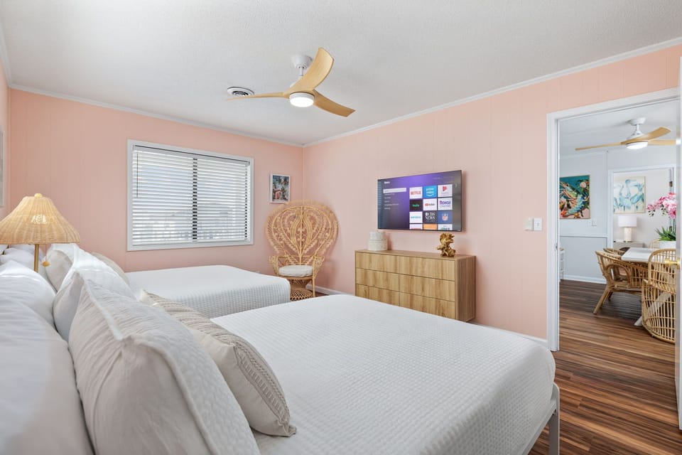 Bedroom 3 features two double beds, water views, and a smart TV, plus convenient bathroom access and ample storage with a closet and dresser—perfect for a comfortable, relaxing stay.