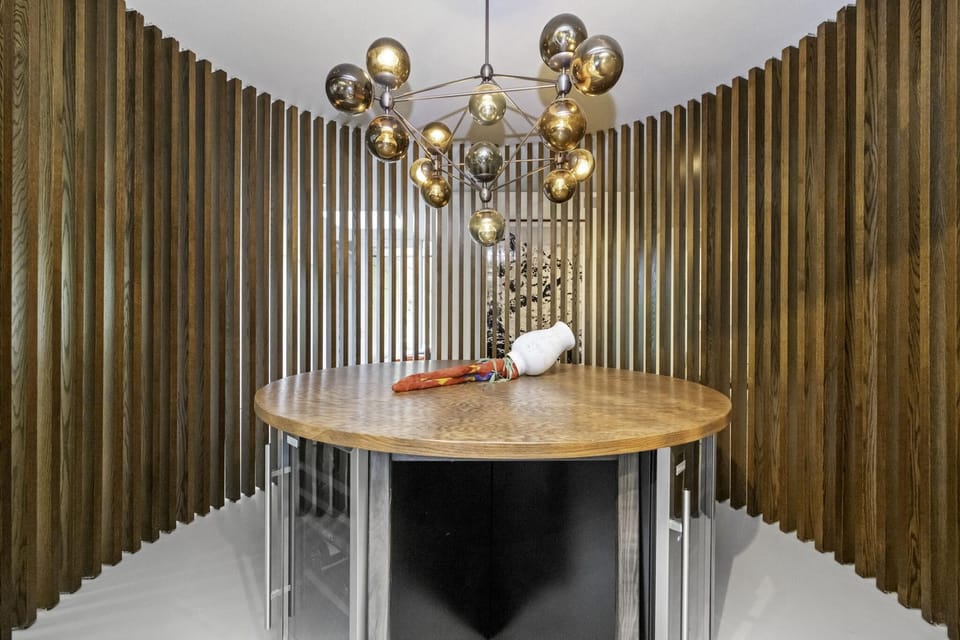 Intimate dining area with sculptural chandelier and curved wood-slat walls