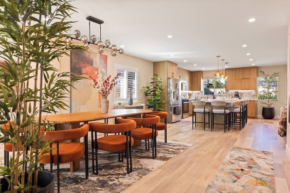 Spacious dining area with a modern wood table, designer upholstered chairs, and a statement chandelier.