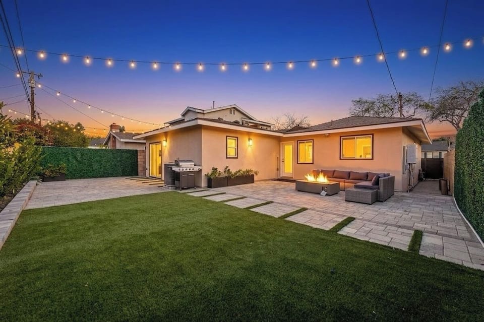 Backyard with a patio, outdoor sectional sofa, fire pit, grill, and string lighting.