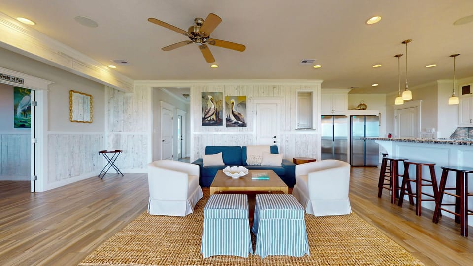 Coastal style living area with comfortable seating, coffee table, and open layout connecting the living room to the kitchen and dining area.