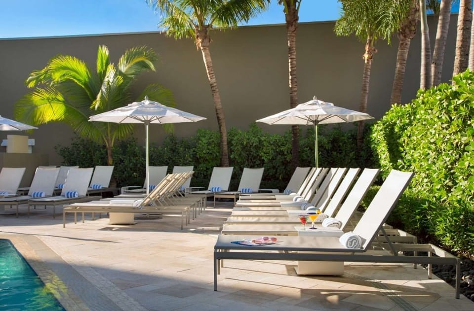 Stretch out poolside on plush loungers under breezy umbrellas.