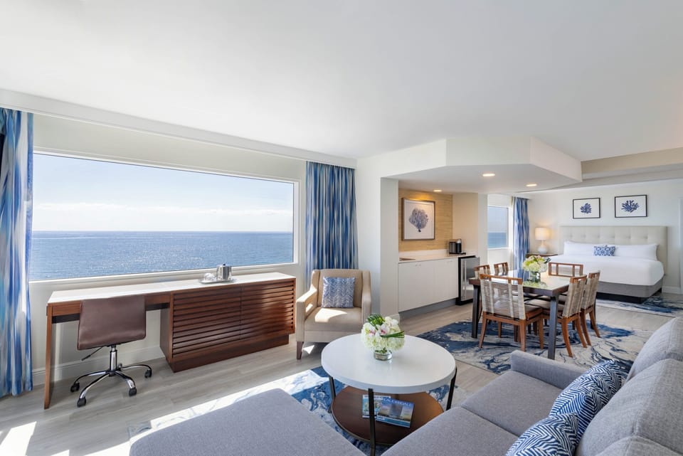 Lounge in sunlit comfort beside a sweeping ocean window.