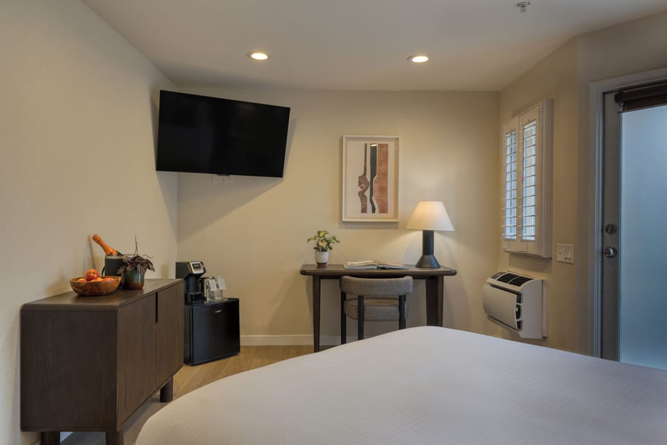 The bedroom features a plush queen bed and a TV.