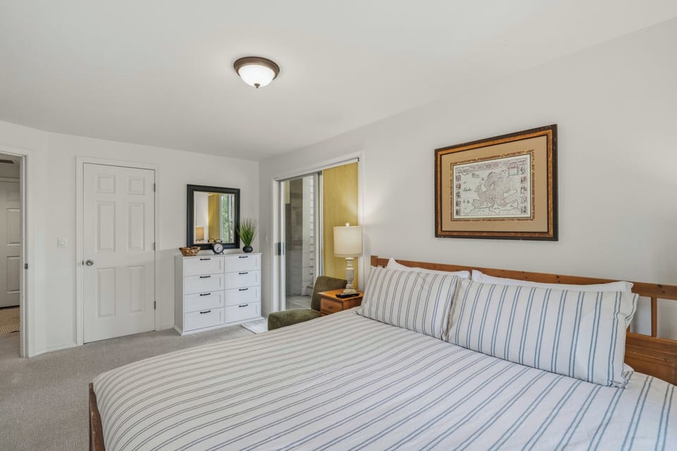 Unwind in your peaceful bedroom featuring a comfortable bed with crisp striped linens and thoughtful touches like bedside lighting.
