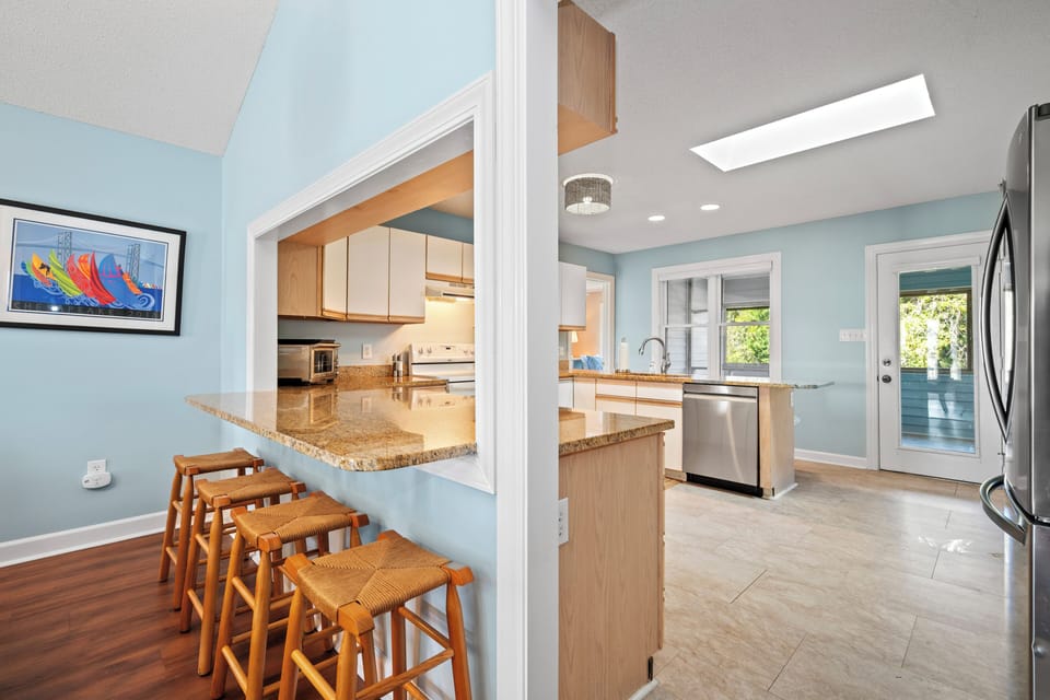 Your bright, open kitchen flows seamlessly into the dining space, featuring granite counters, stainless appliances, and a breakfast bar perfect for morning coffee.