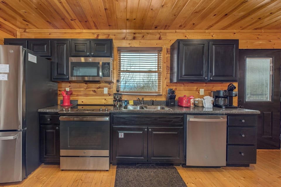 Cook your favorite meals in this fully-equipped kitchen featuring modern appliances, granite countertops, and warm cabin charm.