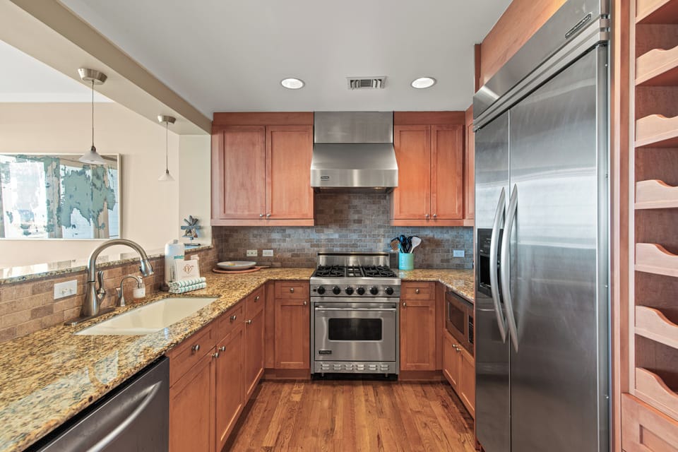 Step into your fully equipped kitchen with granite counters, stainless steel appliances, and warm wood cabinets perfect for preparing memorable meals.