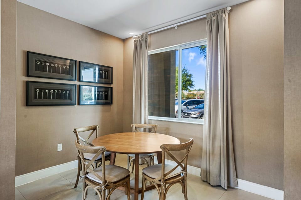 Cozy dining area with natural light and rustic wooden chairs around a round table.