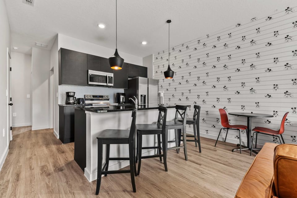 Modern kitchen with black cabinetry and a playful mickey mouse wallpaper accent wall