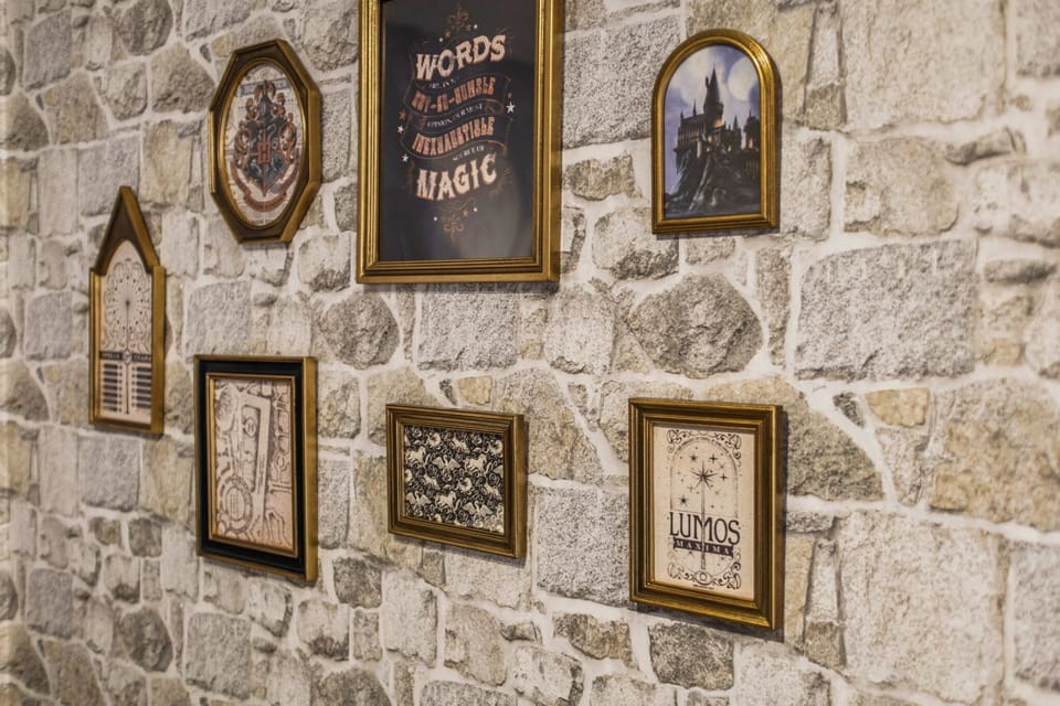 A stone wall decorated with framed magical-themed artwork creates a cozy and whimsical atmosphere.