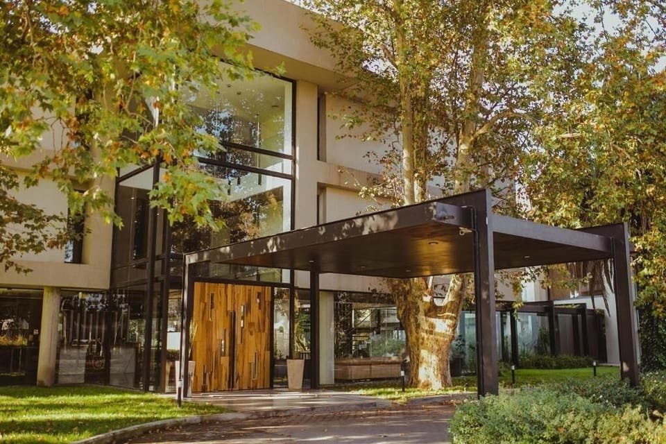 Arrive to a sleek, sunlit entrance framed by greenery.
