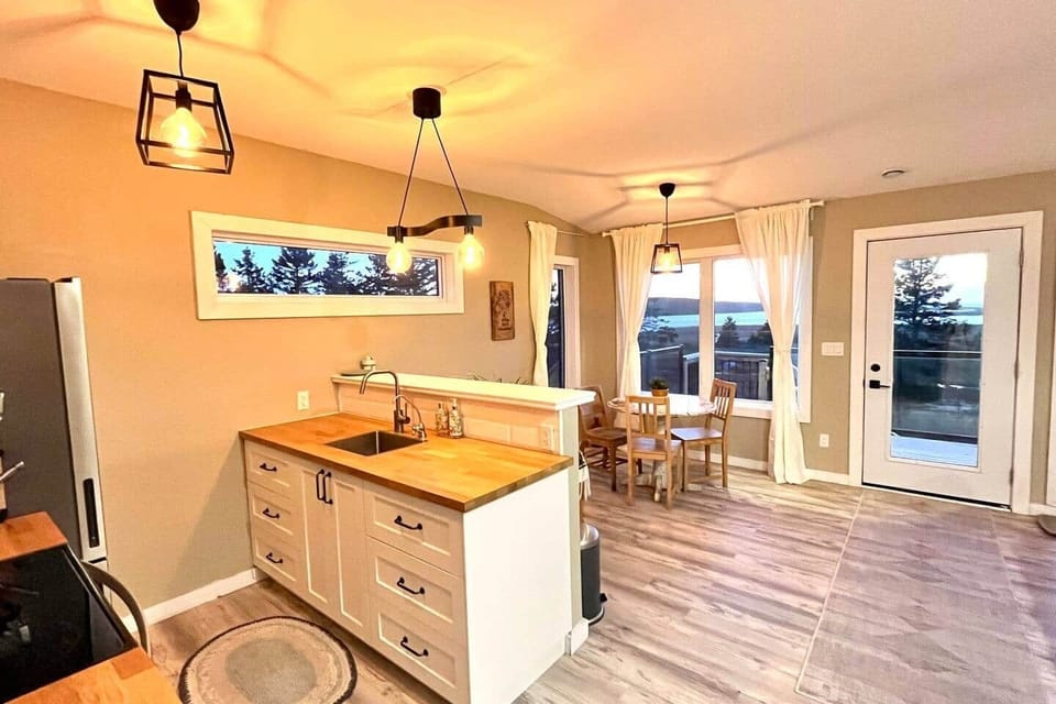 Bright open kitchen-dining with deck access and sunset tree views