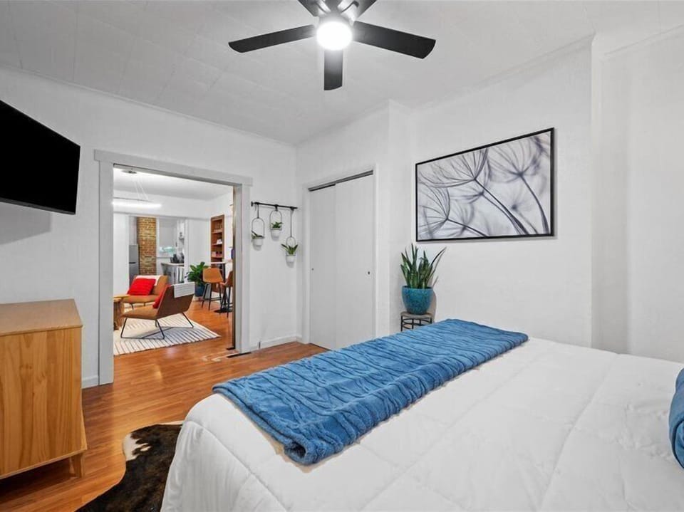 Bright, airy bedroom with wood floors, TV, and easy access to living space