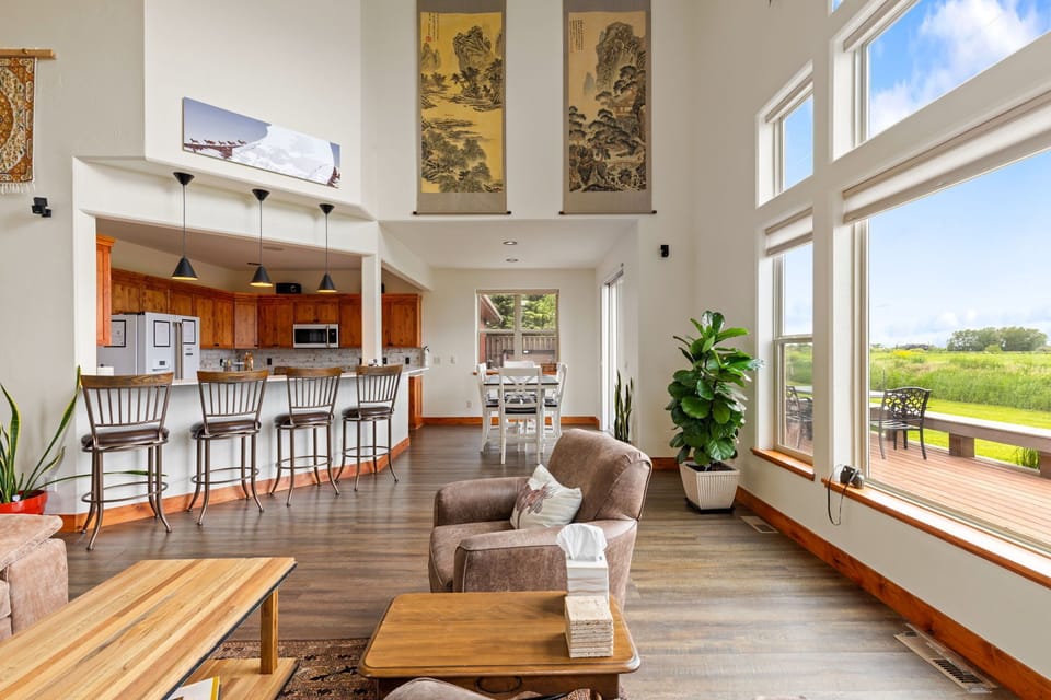Bright open living space with soaring windows, bar seating, and scenic views