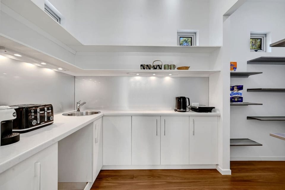 Bright modern kitchen featuring appliances, open shelving, and warm wood floors for family convenience.